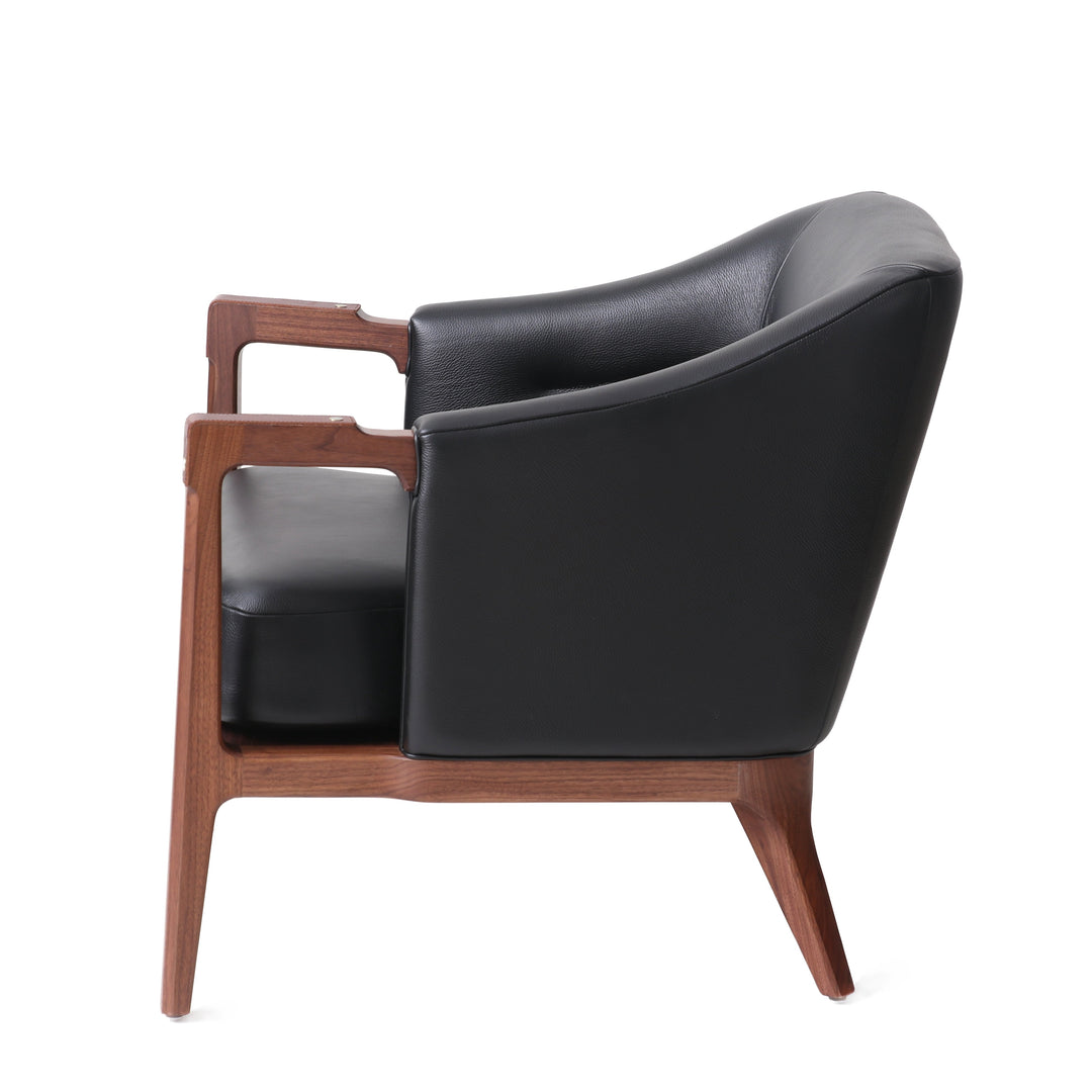 Modern lounge chair with natural walnut wooden frame, black leather upholstery, and brass details, perfect for contemporary living rooms or stylish office spaces.